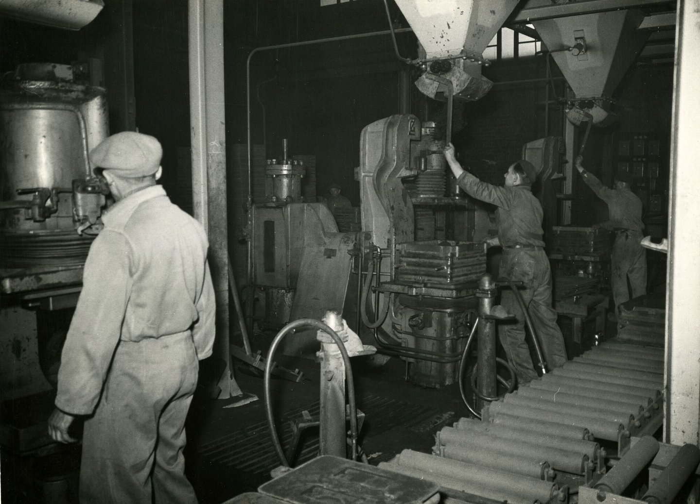 Arbeiders vullen vormkasten aan vormmachine in metaalgieterij van machinebouwer SEM-Carels in Gent